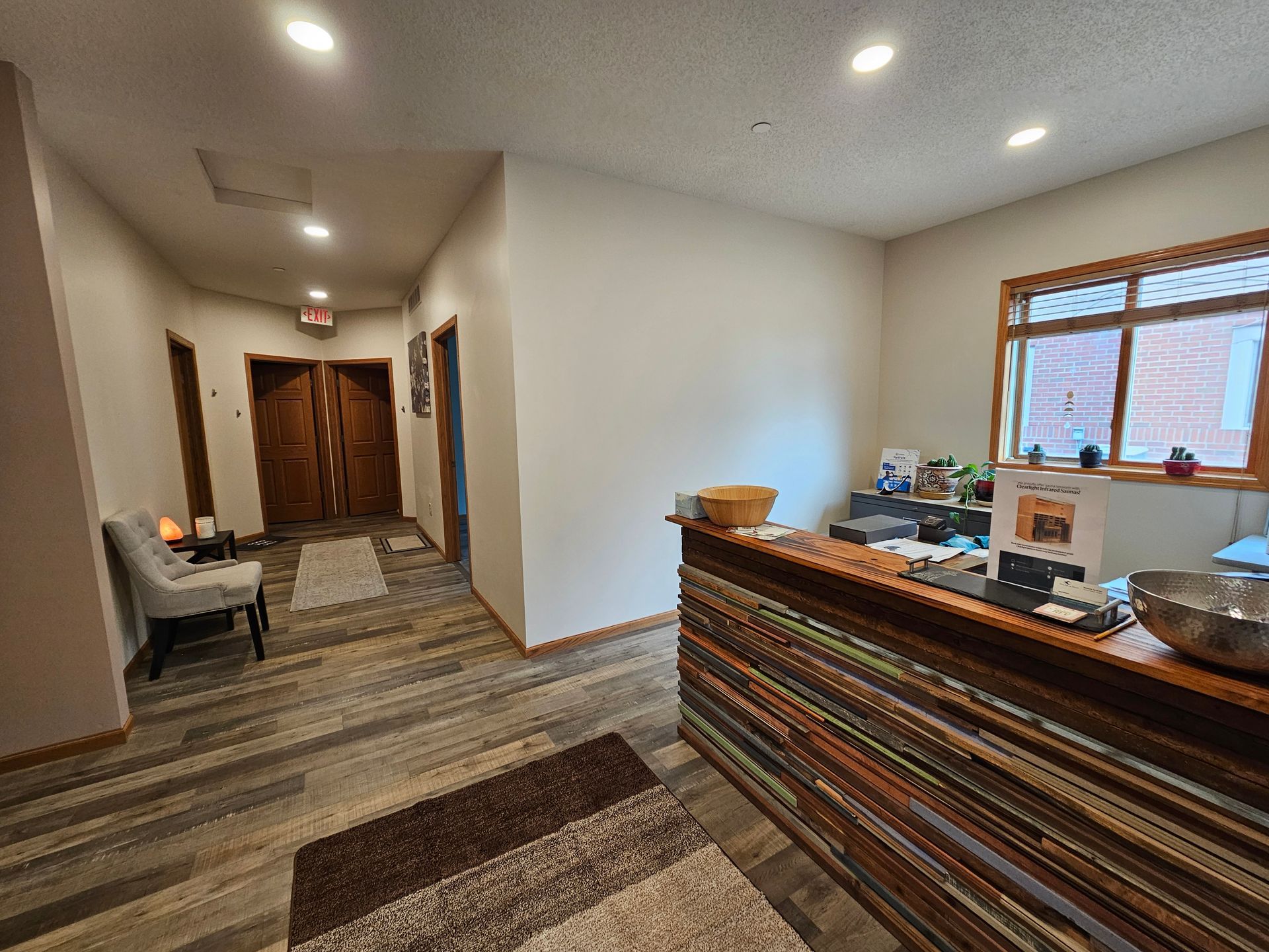 Reception area with wooden counter, hallway with doors, and waiting area with chair.