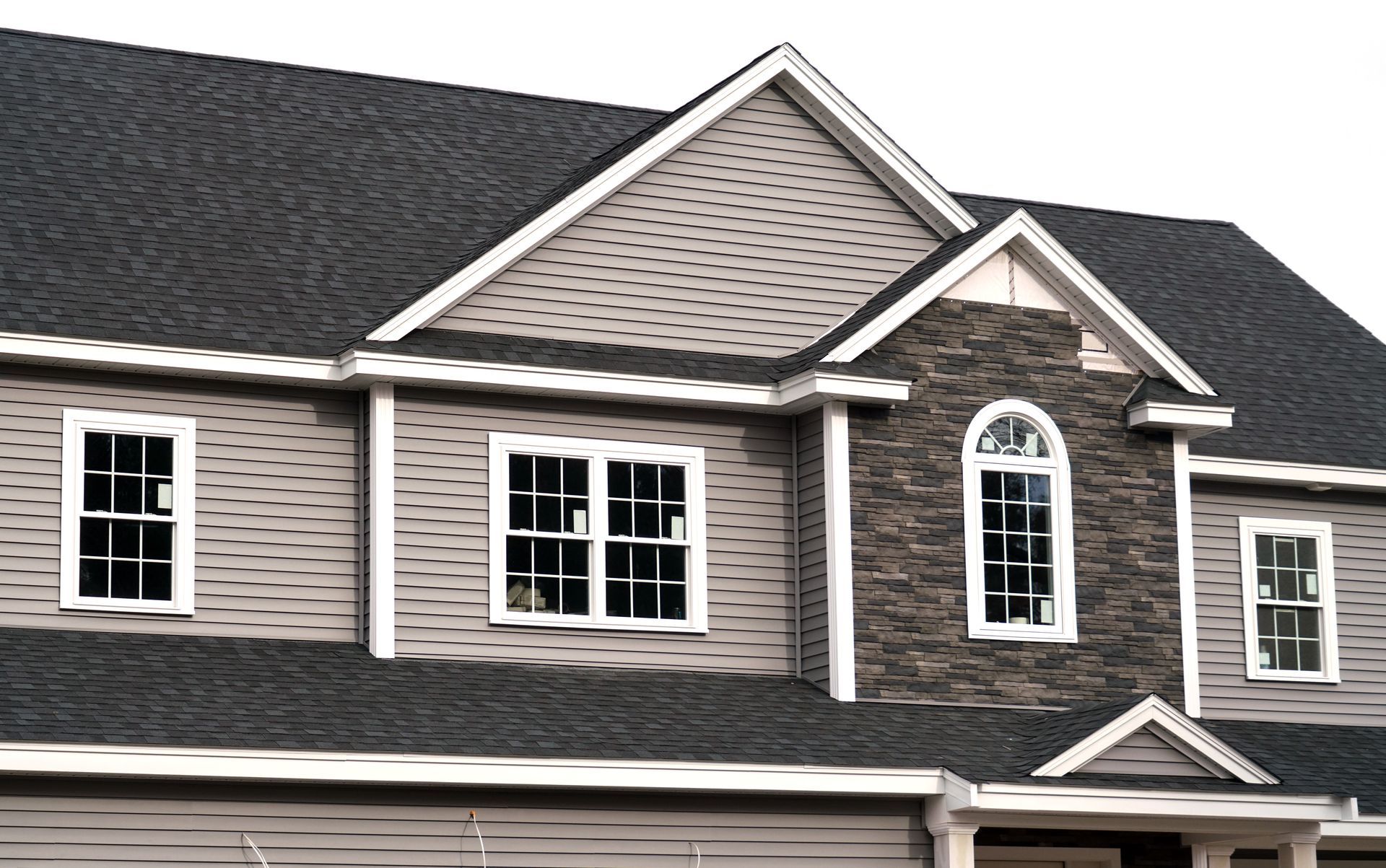 A large house with a black roof and a stone chimney.