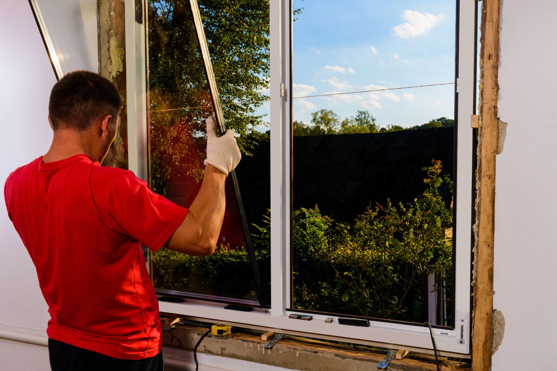 A man in a red shirt is installing a window.