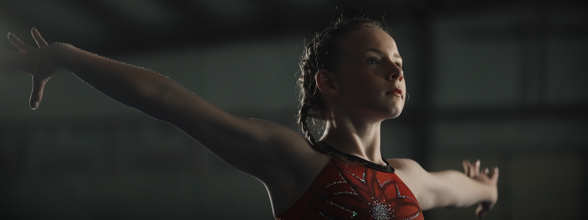 A close up of a female gymnast with her arms outstretched.