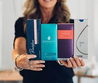 Woman holding four product boxes: Restylane, Skinvive, Juvederm Ultra XC, and HA2.