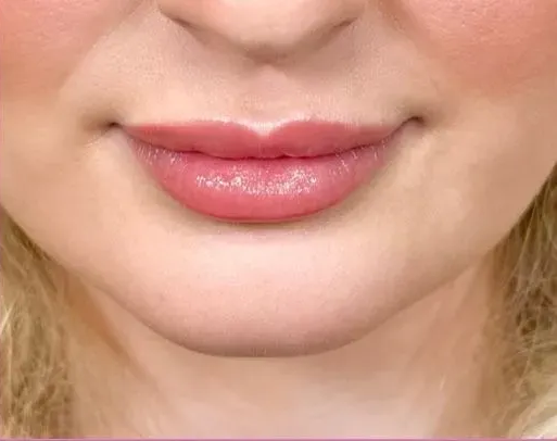 Close-up of a person's lips. The lips are full and have a pink, glossy finish.