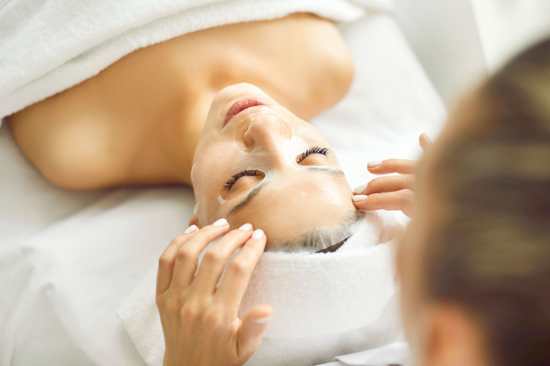 Woman receiving a facial treatment with mask in a spa.