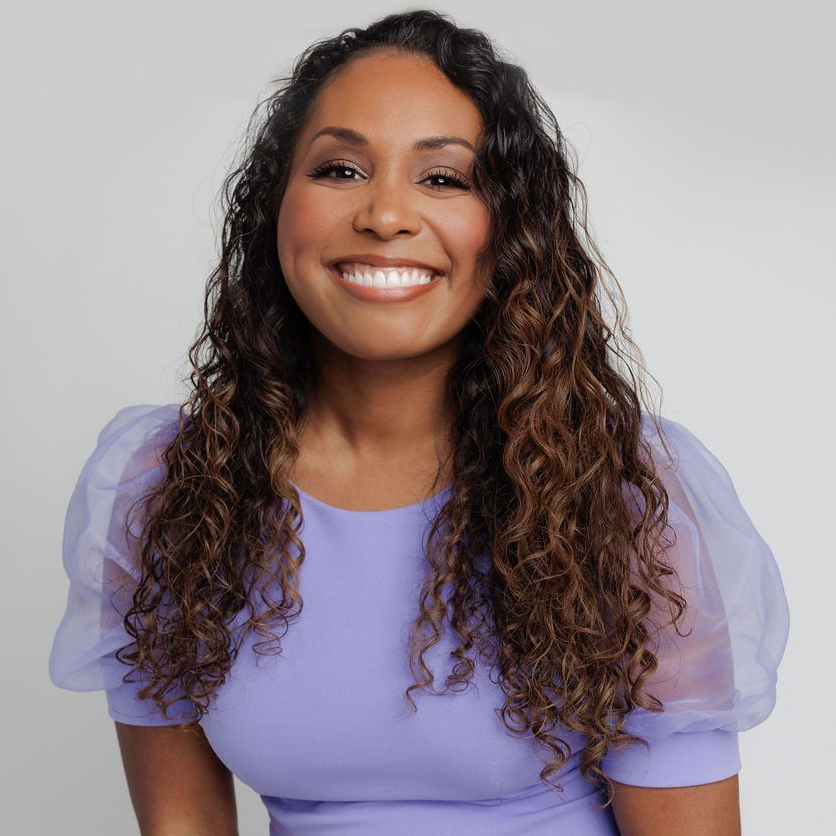 Smiling woman in a lavender top against a light gray background
