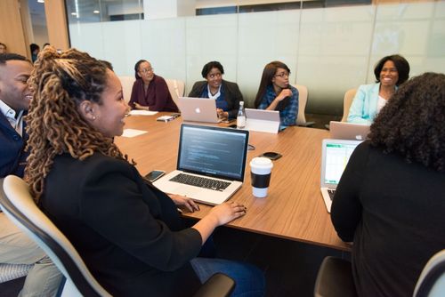 People seated around a conference table in a meeting room with laptops and coffee cups