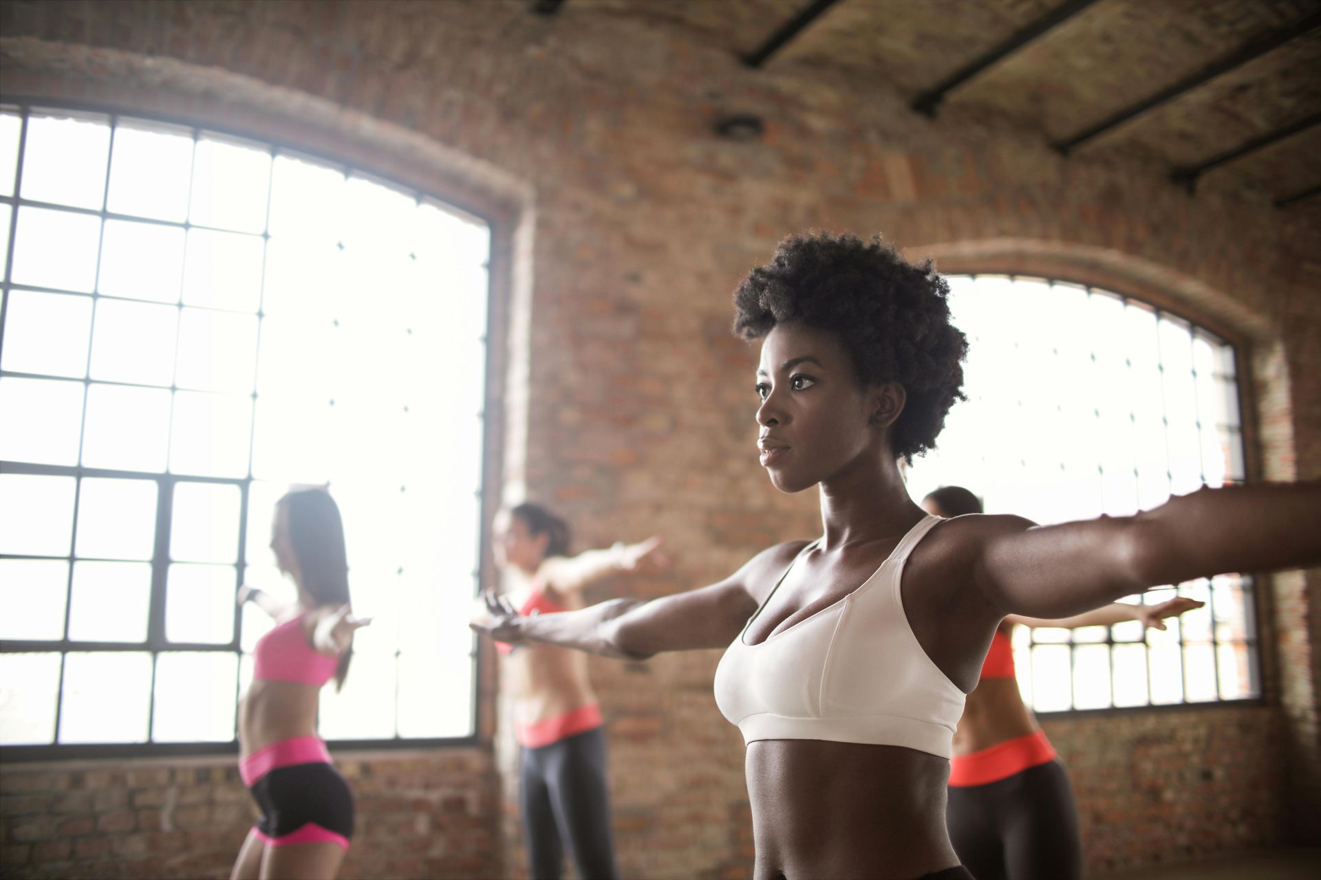 People exercising with arms extended in a bright studio with large windows