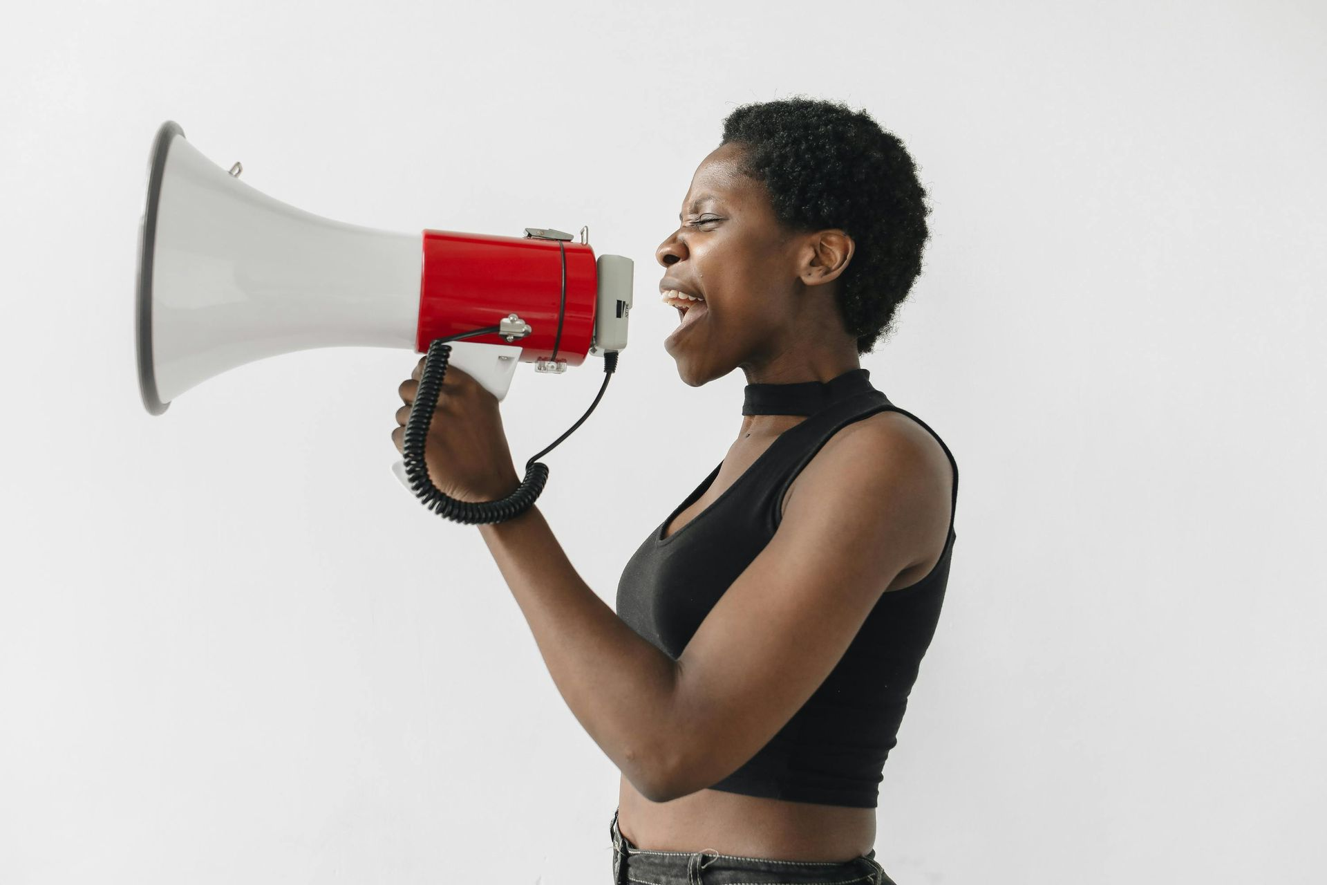 Person speaking into a red-and-white megaphone against a plain white background