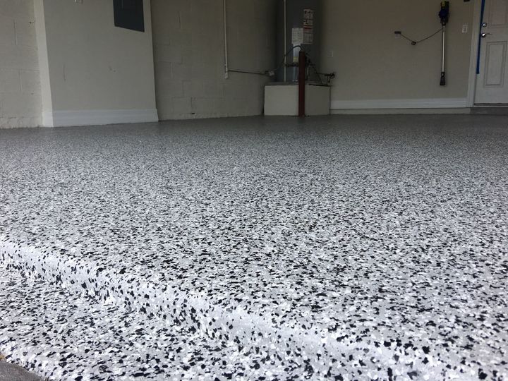 Garage floor with a gray and white speckled epoxy flake coating.