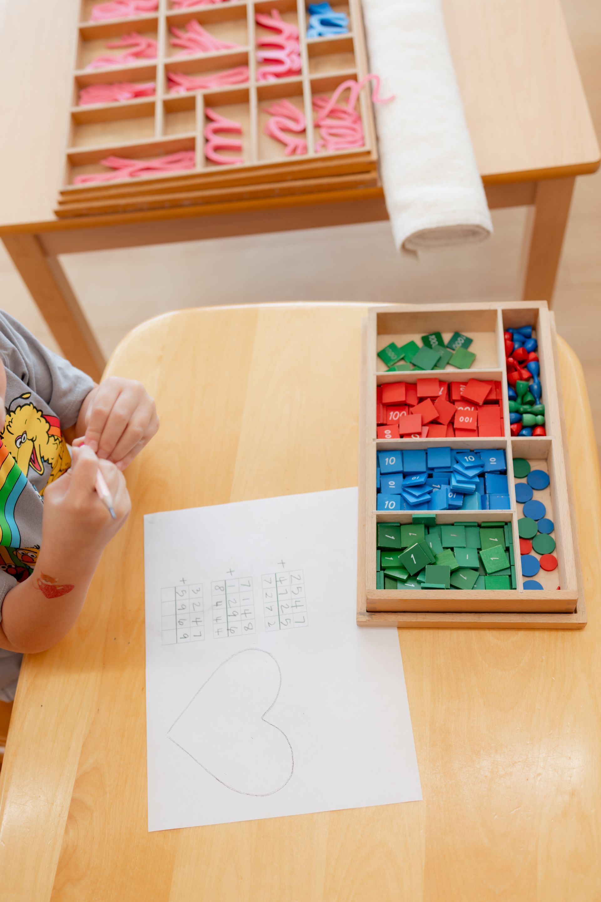Child at a table with a piece of paper and the stamp game.