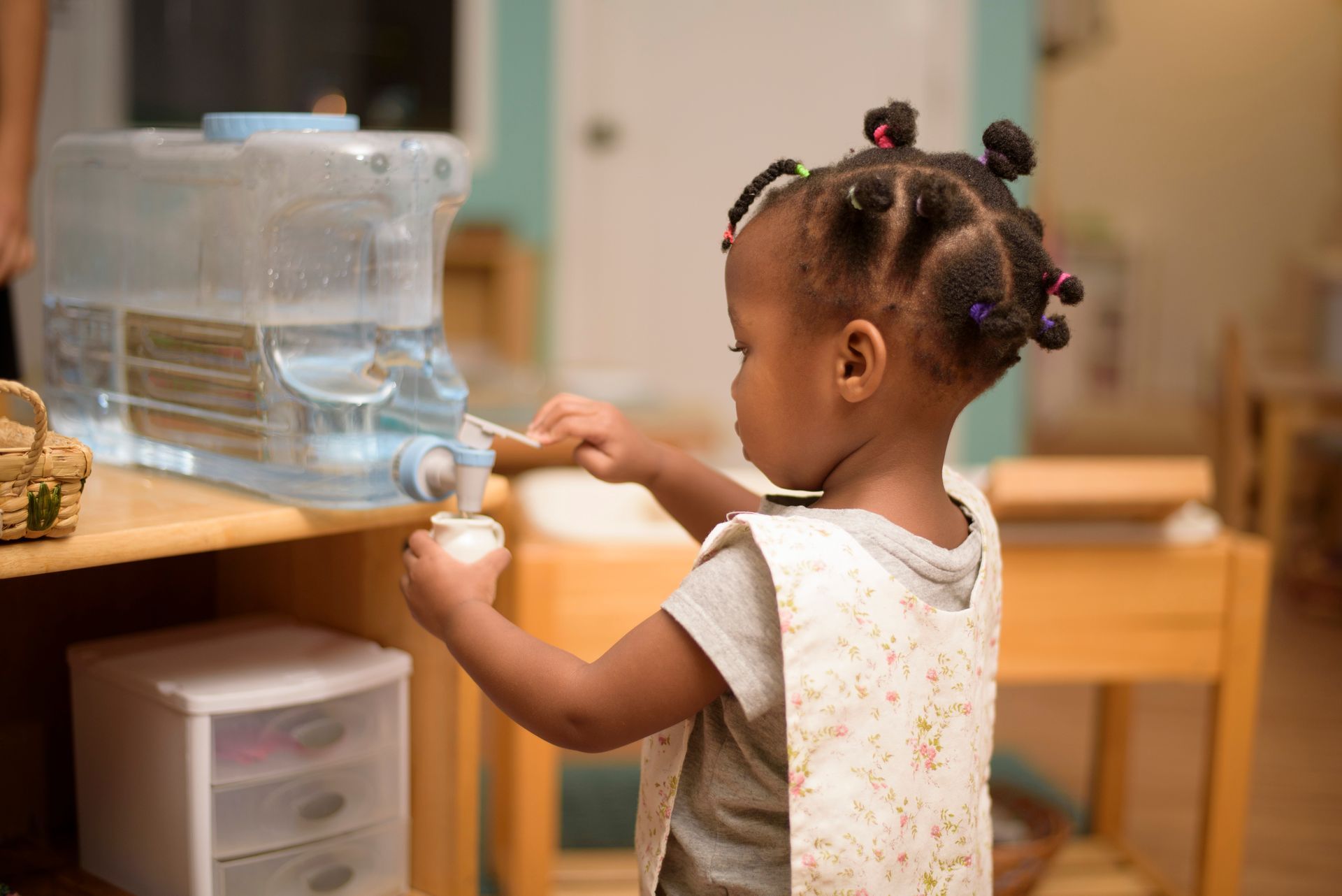 Young child using a water dispenser in a classroom setting
