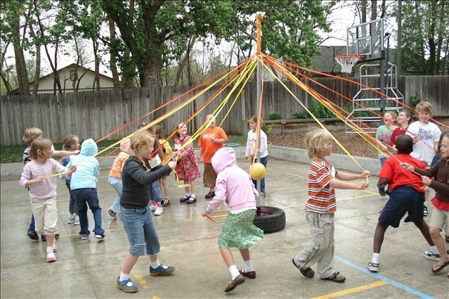 a group of children are playing with ribbons and a tire