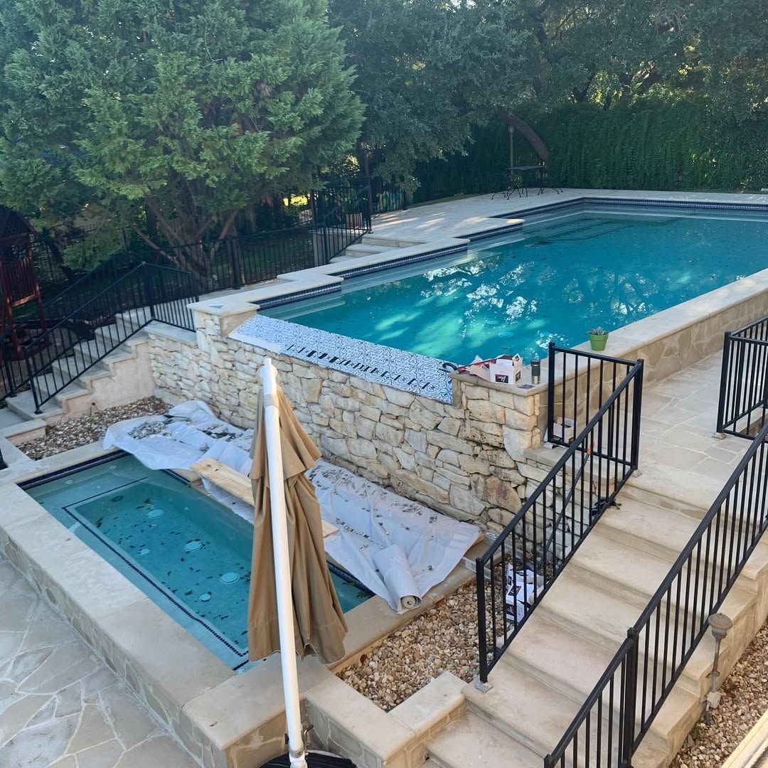 Backyard pool area with an upper swimming pool, hot tub, stone steps, and lounge chairs under trees