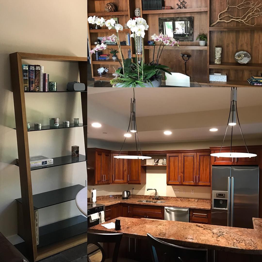 Modern kitchen and living room with wood cabinets, granite counters, shelving, and a potted orchid