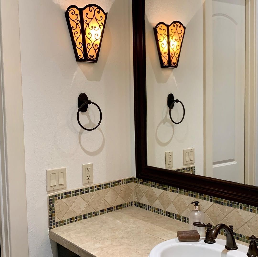 Bathroom vanity with mirror, wall sconces, countertop, and sink.