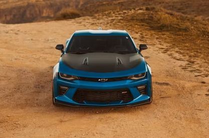 Blue sports car on a dirt road in a rocky desert landscape