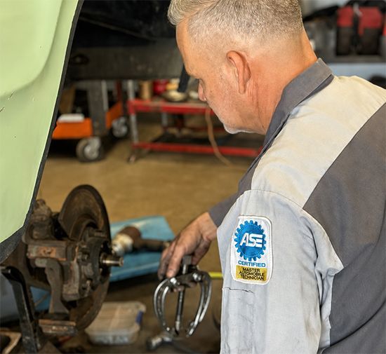 Mechanic working on a car brake assembly in an auto repair shop