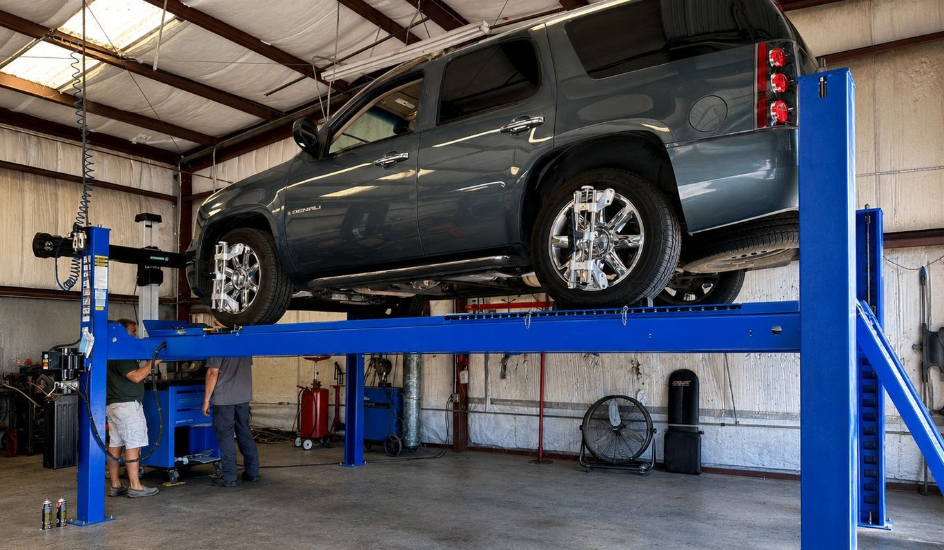 Gray SUV on a blue hydraulic car lift in an auto repair garage