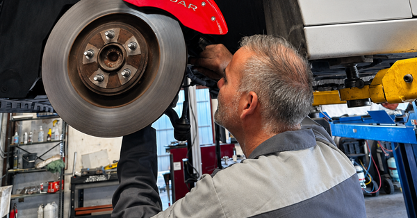 Mechanic inspecting a car’s front wheel and brake in an auto shop