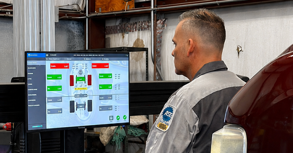 Technician at a monitor with machine-control dashboard in an industrial workshop