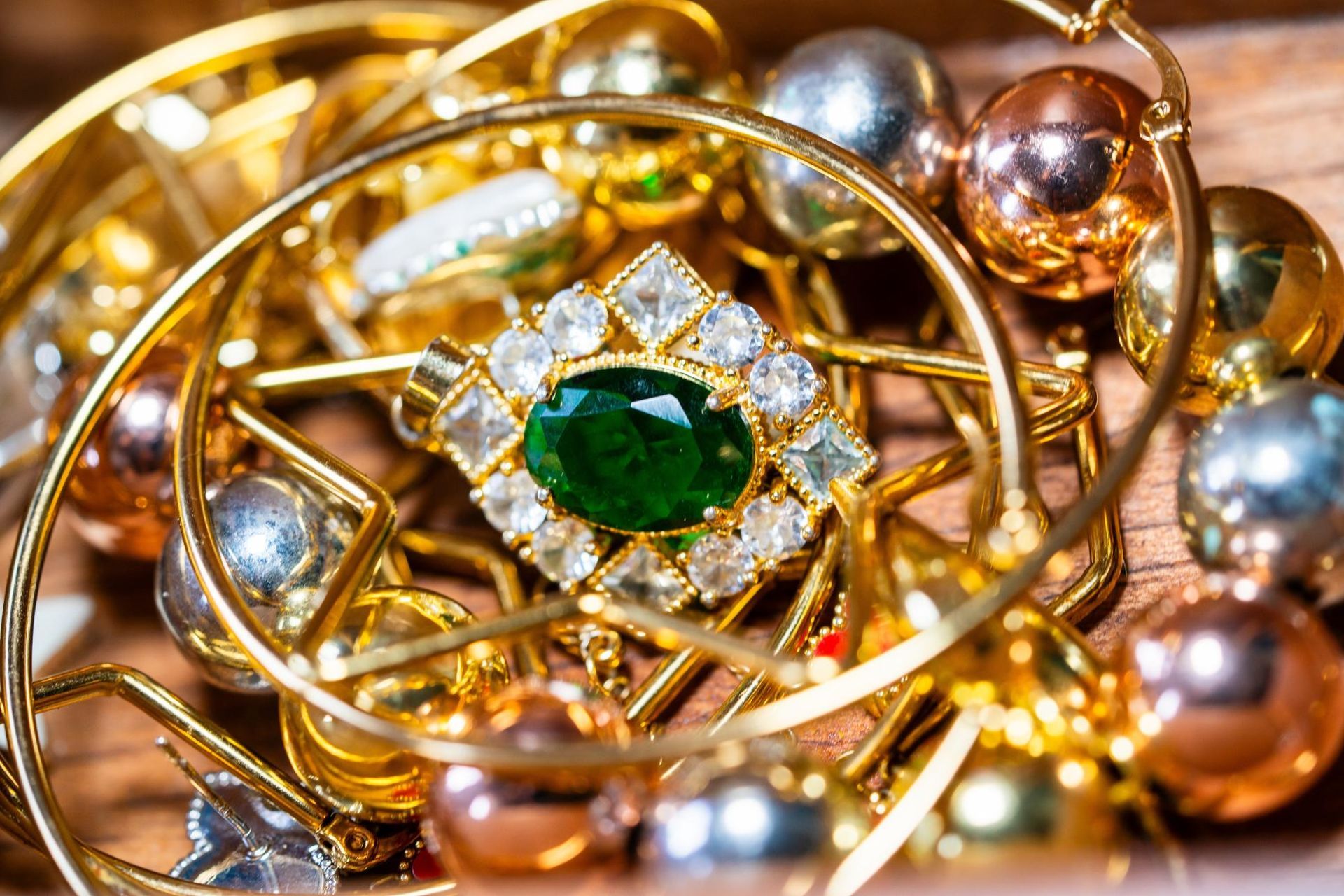 Gold jewelry with a green gemstone and pearls in a close-up pile