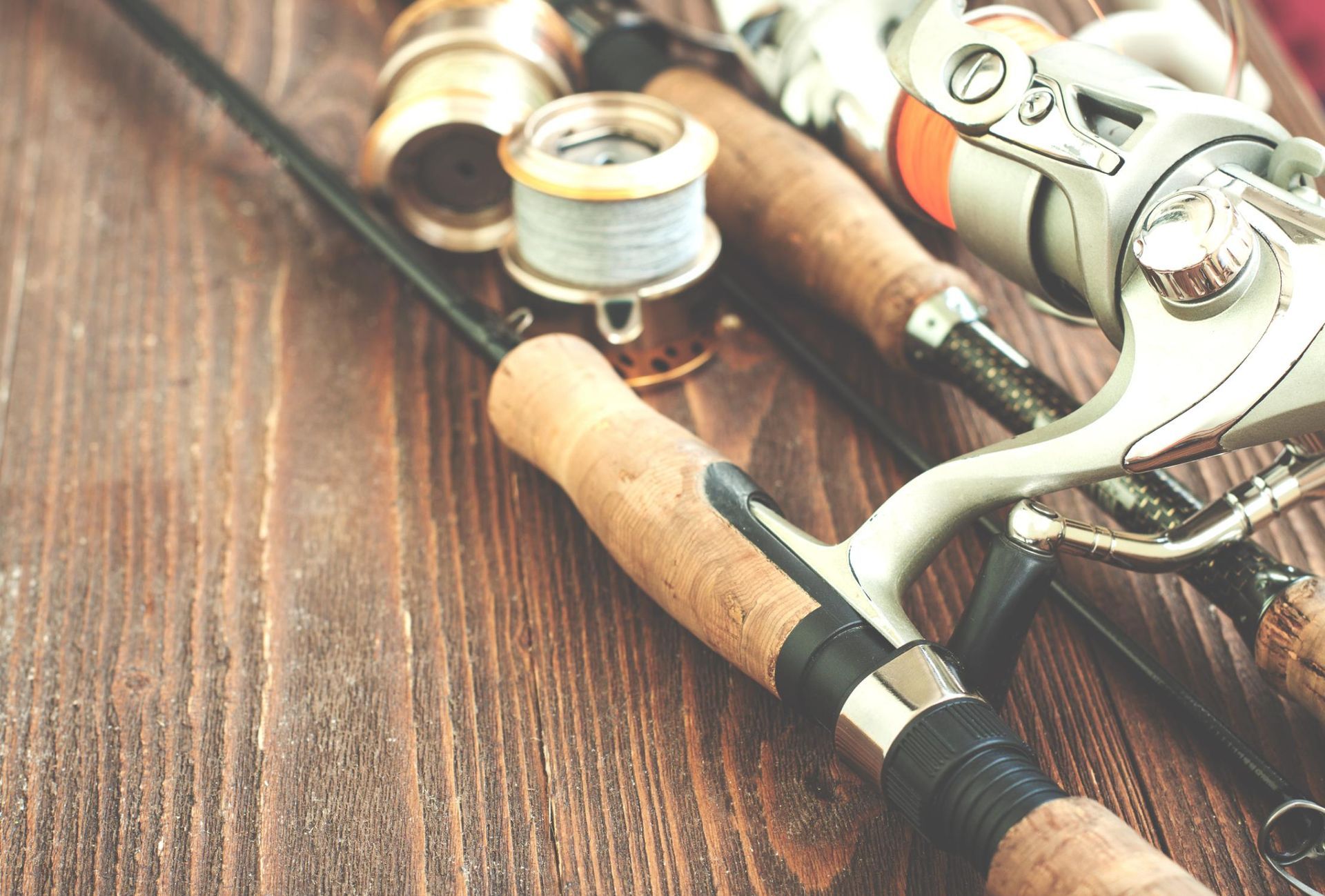 Fishing rods and reels on a wooden surface, with a spool of fishing line