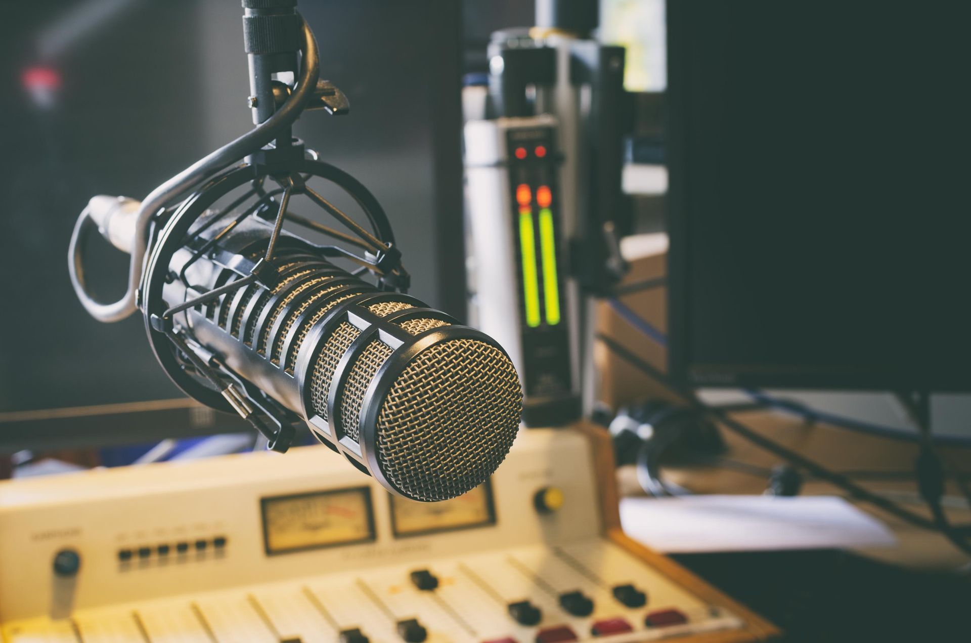 Close-up of a studio microphone with mixer controls in the background