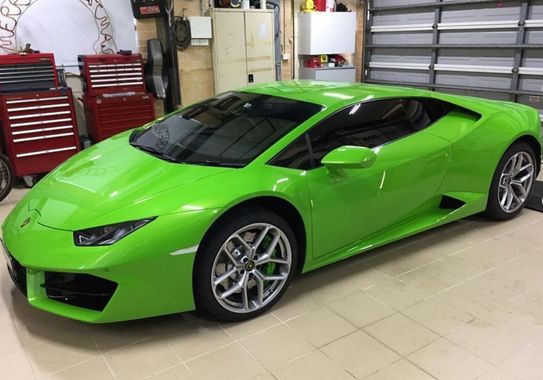 A green lamborghini huracan is parked in a garage with new window tinting via a mobile service.