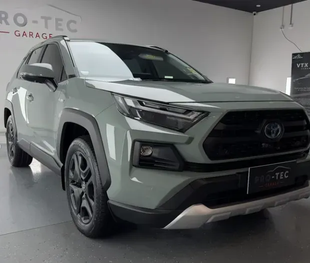A green car is parked in front of a wall that says Pro-tec garage with new tint in Sydney.