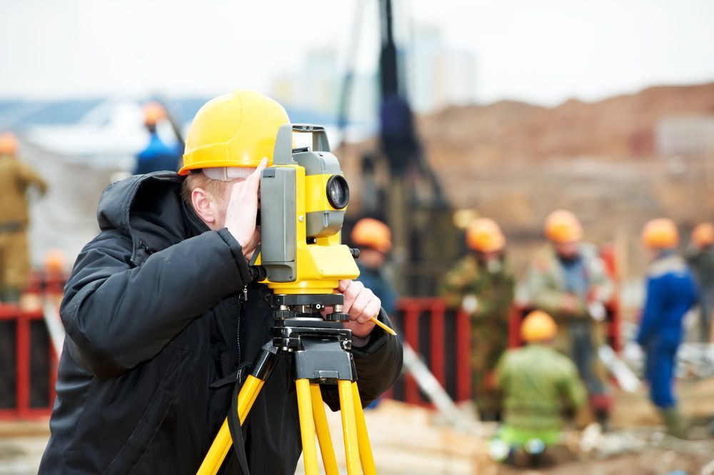 A Man Is Using A Theodolite On A Construction Site — CalCo Surveyors Pty Ltd in Gloucester, NSW