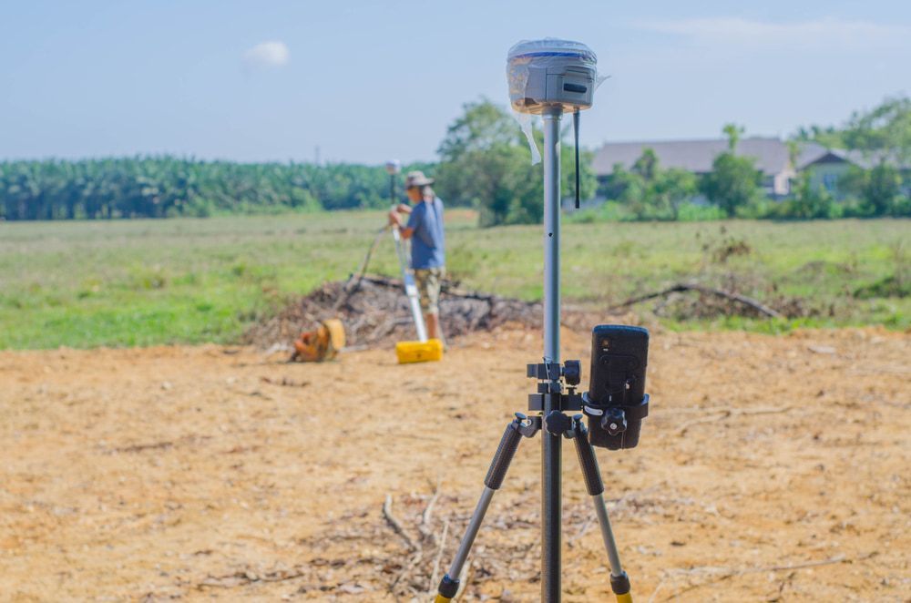 A Man Is Standing In A Field Using A Gps Device  — CalCo Surveyors Pty Ltd in Old Bar, NSW