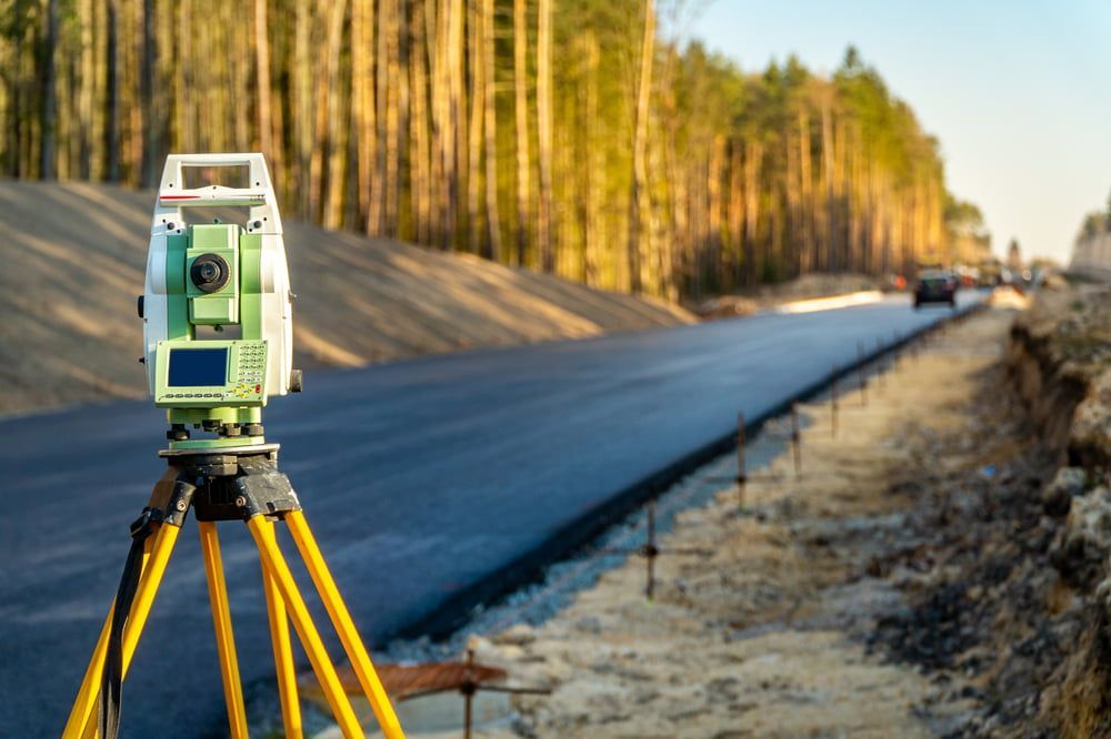 A Total Station Is Sitting On A Tripod On The Side Of A Road — CalCo Surveyors Pty Ltd in Diamond Beach, NSW