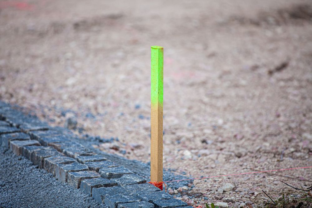 A Wooden Pole With A Green Marker On It Is Sitting On The Ground  — CalCo Surveyors Pty Ltd in Nabiac, NSW