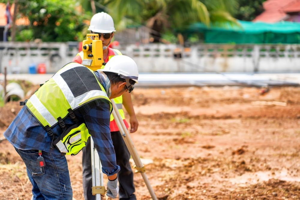 Two Construction Workers Are Working On A Construction Site — CalCo Surveyors Pty Ltd in Taree, NSW