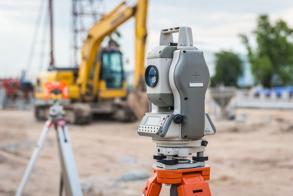 A Theodolite Is Sitting On A Tripod On A Construction Site — CalCo Surveyors Pty Ltd in Stroud, NSW