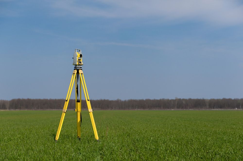 A Yellow Tripod Is Sitting In The Middle Of A Grassy Field — CalCo Surveyors Pty Ltd in Gloucester, NSW