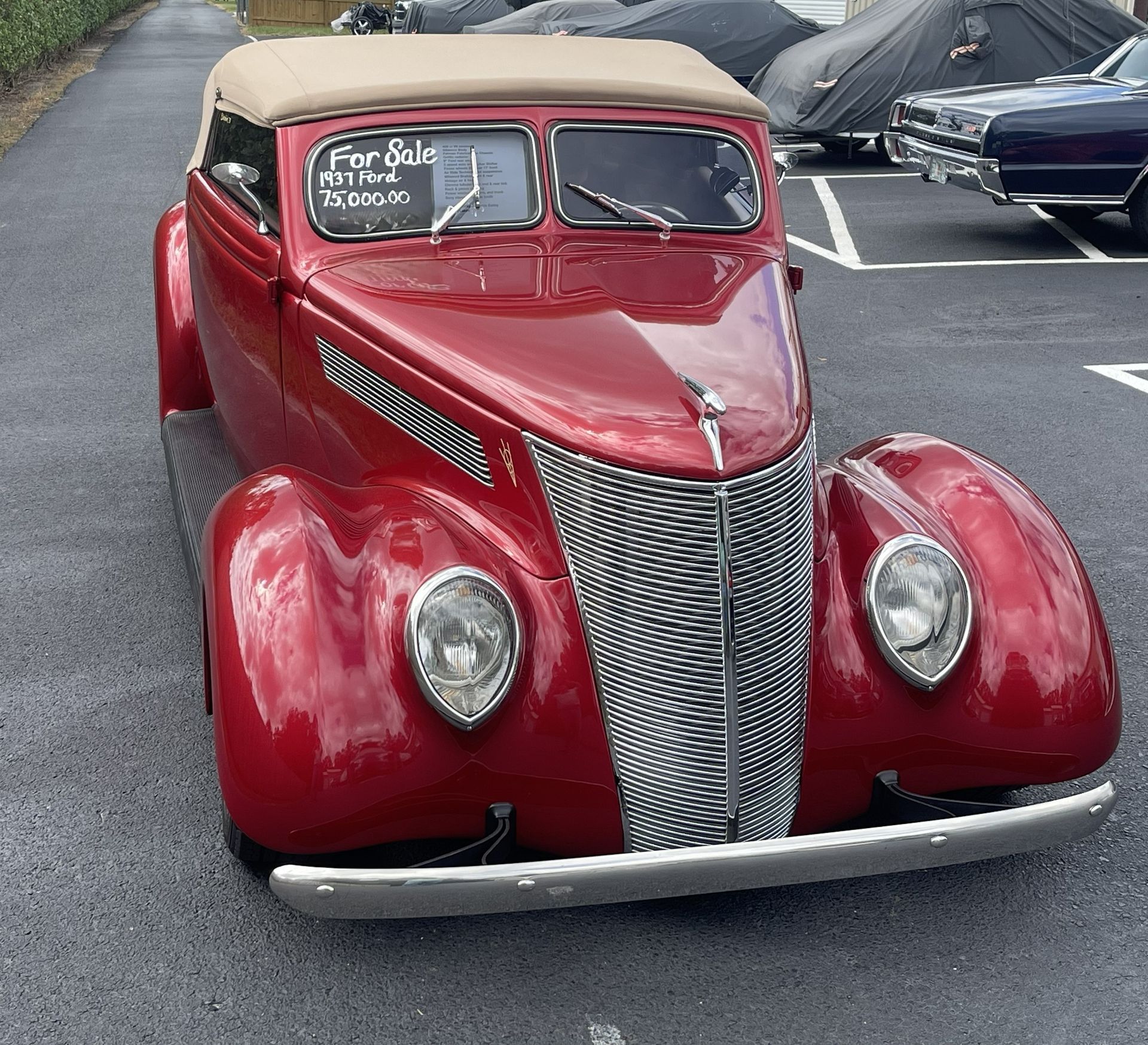 Red classic convertible car with tan top parked on asphalt.