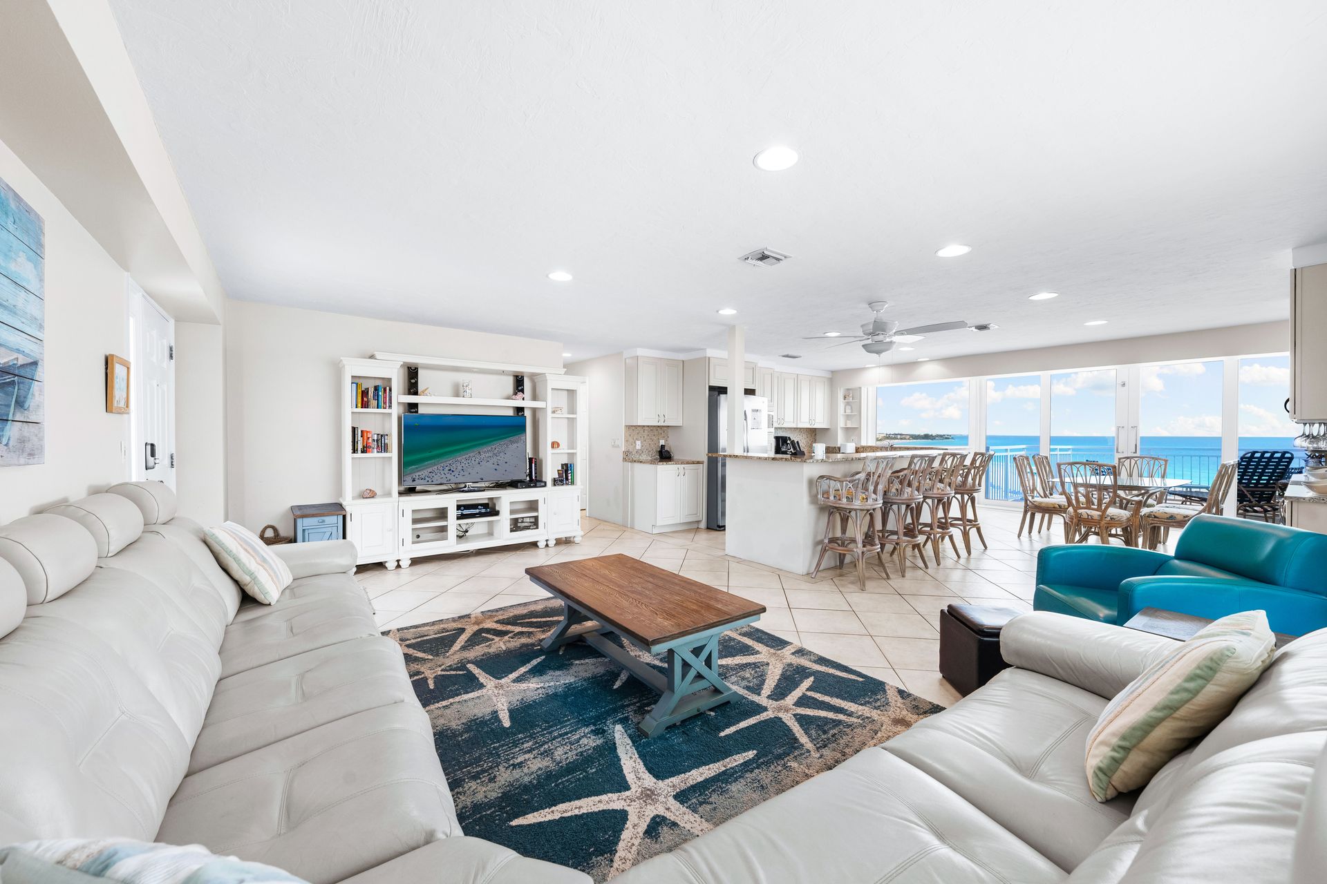 A living room filled with furniture and a television with a view of the ocean.