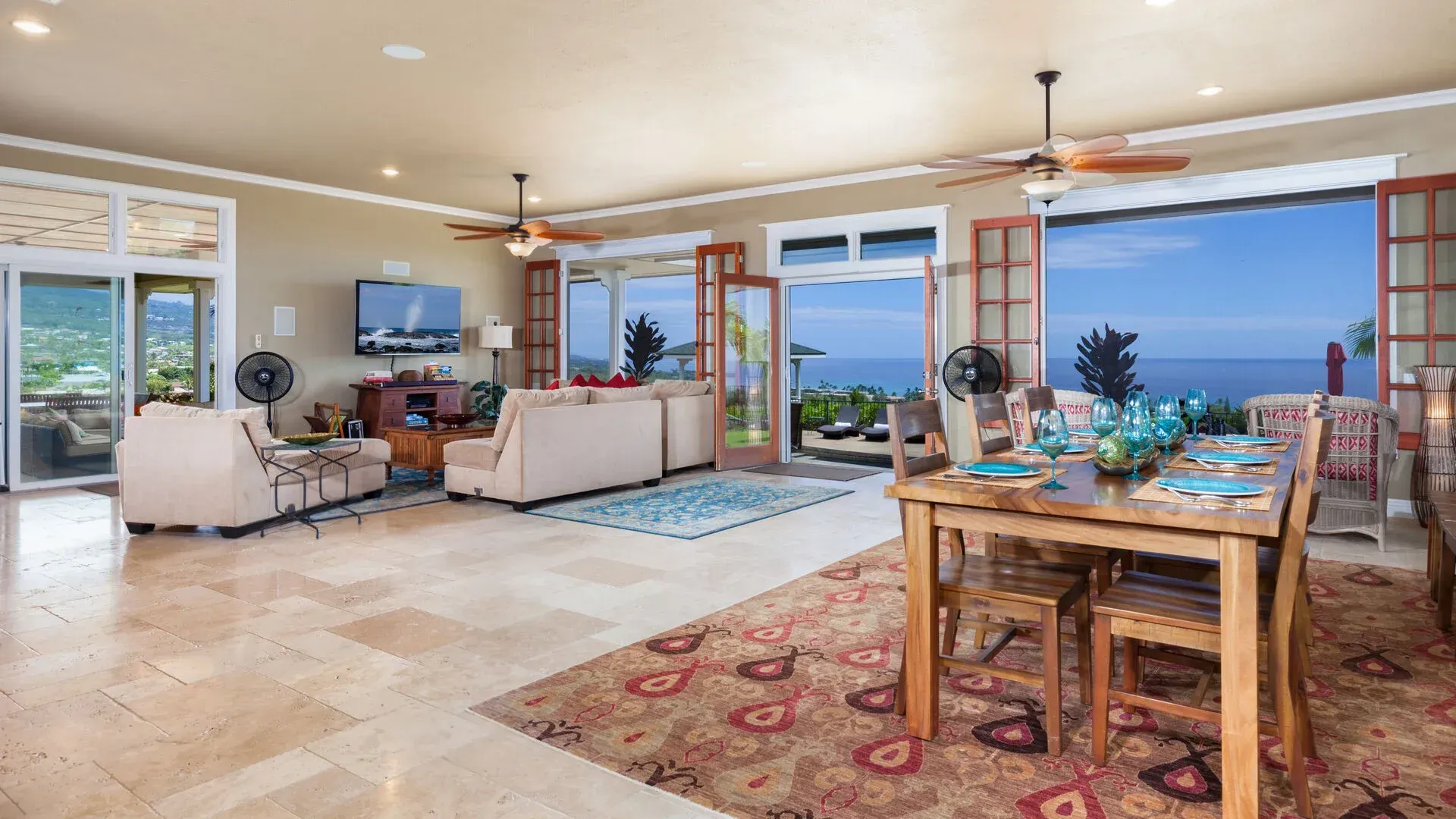 A large living room with a dining table and chairs and a view of the ocean.