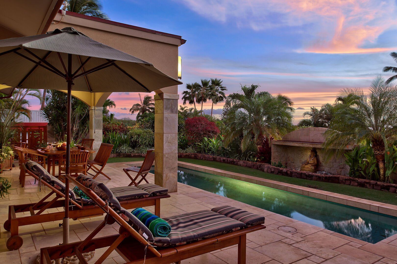 A patio with chairs and umbrellas next to a swimming pool.