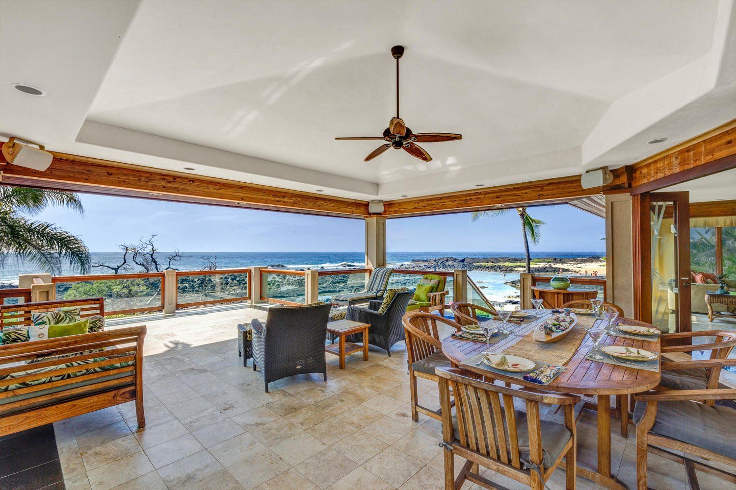 Outdoor dining area with ocean view, including tables, chairs, and a ceiling fan.