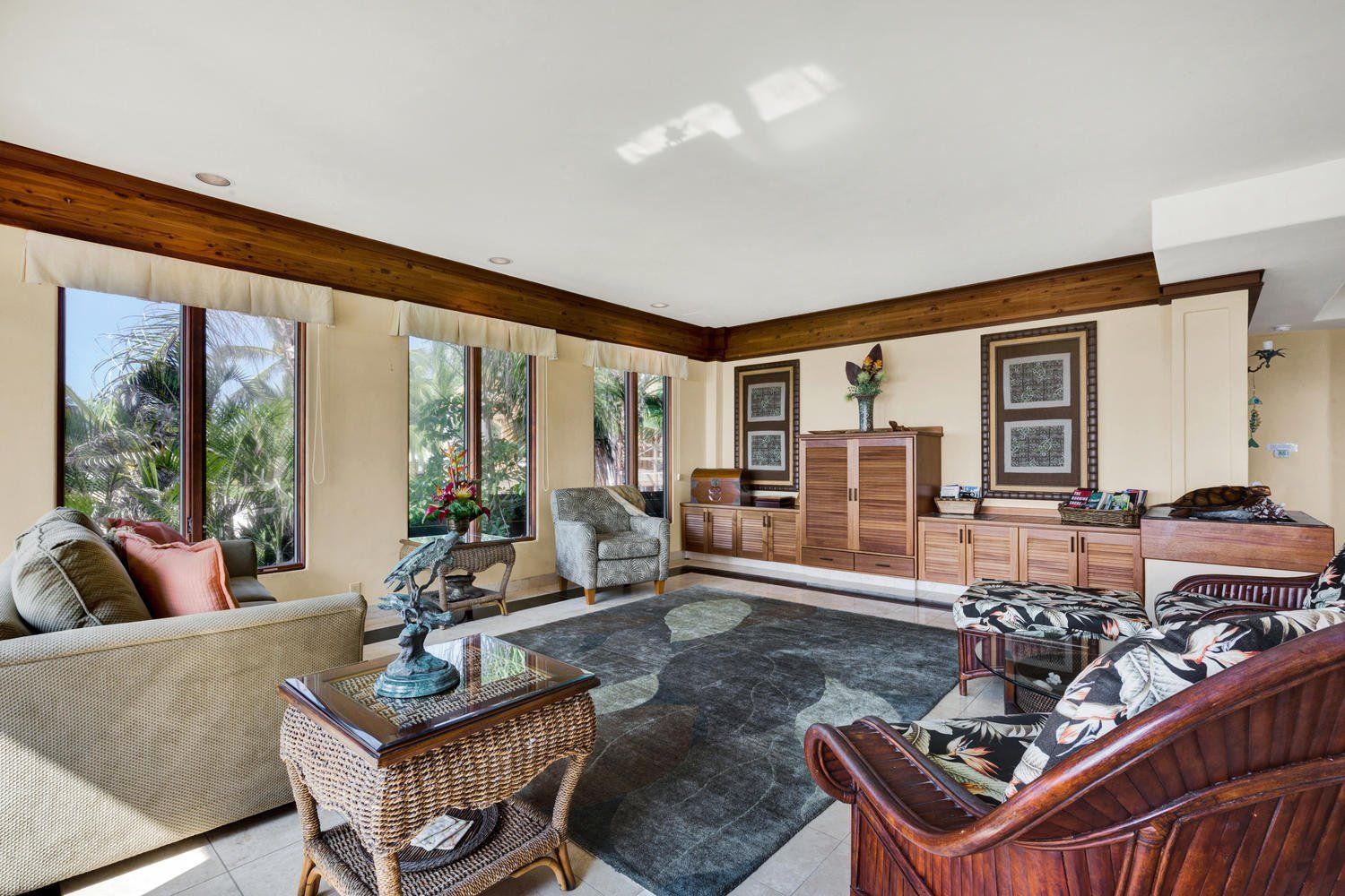 Living room with beige walls, wooden trim, windows, and various furniture.