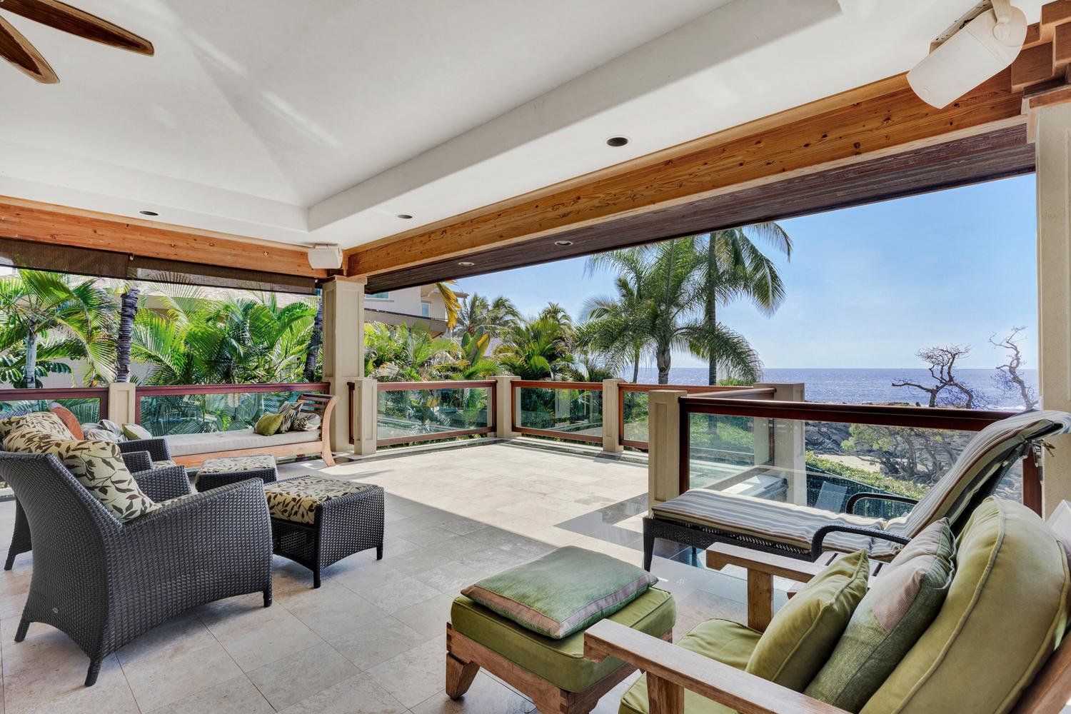 Patio with seating overlooking ocean and tropical foliage.