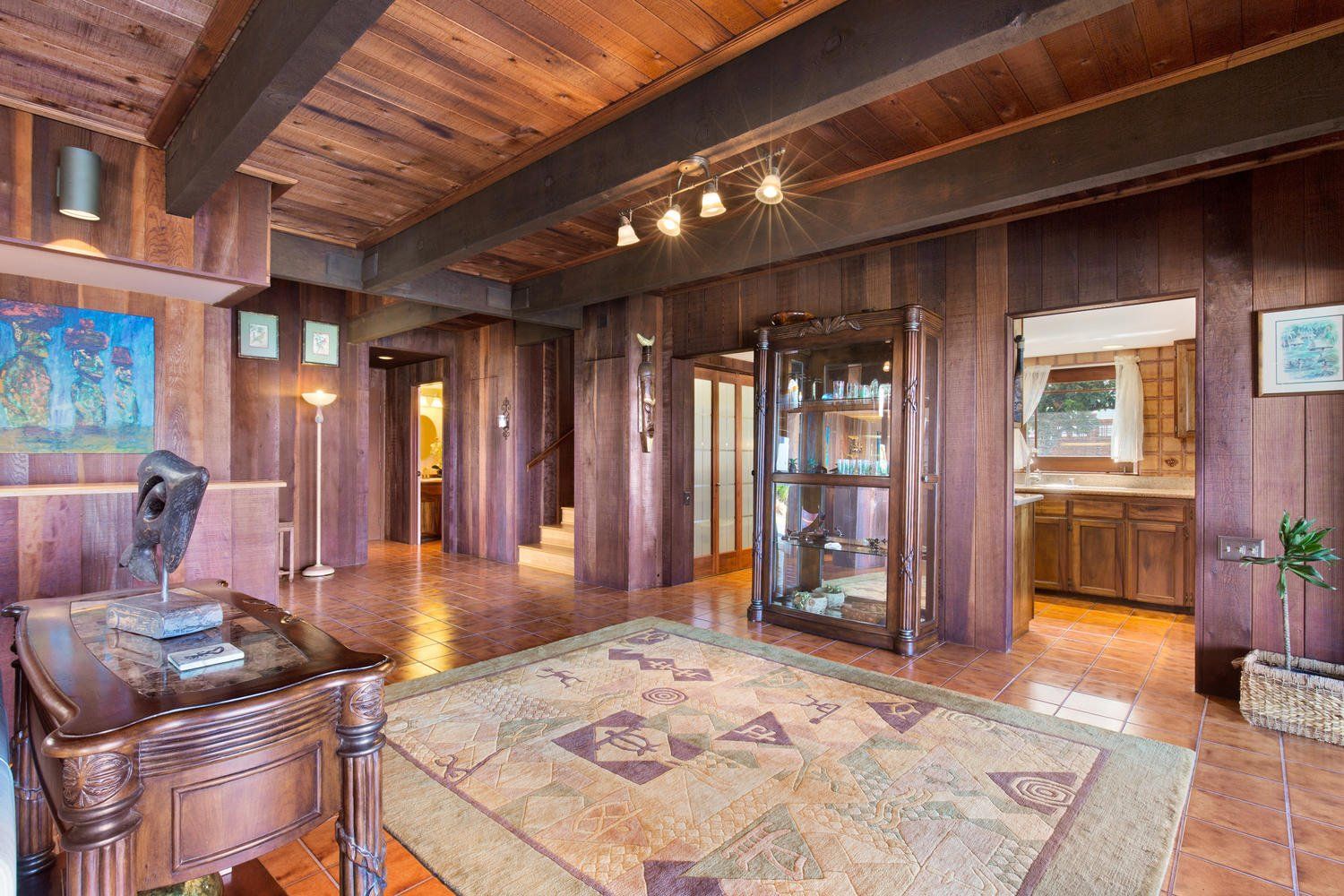 A living room with wood paneling and a rug on the floor.