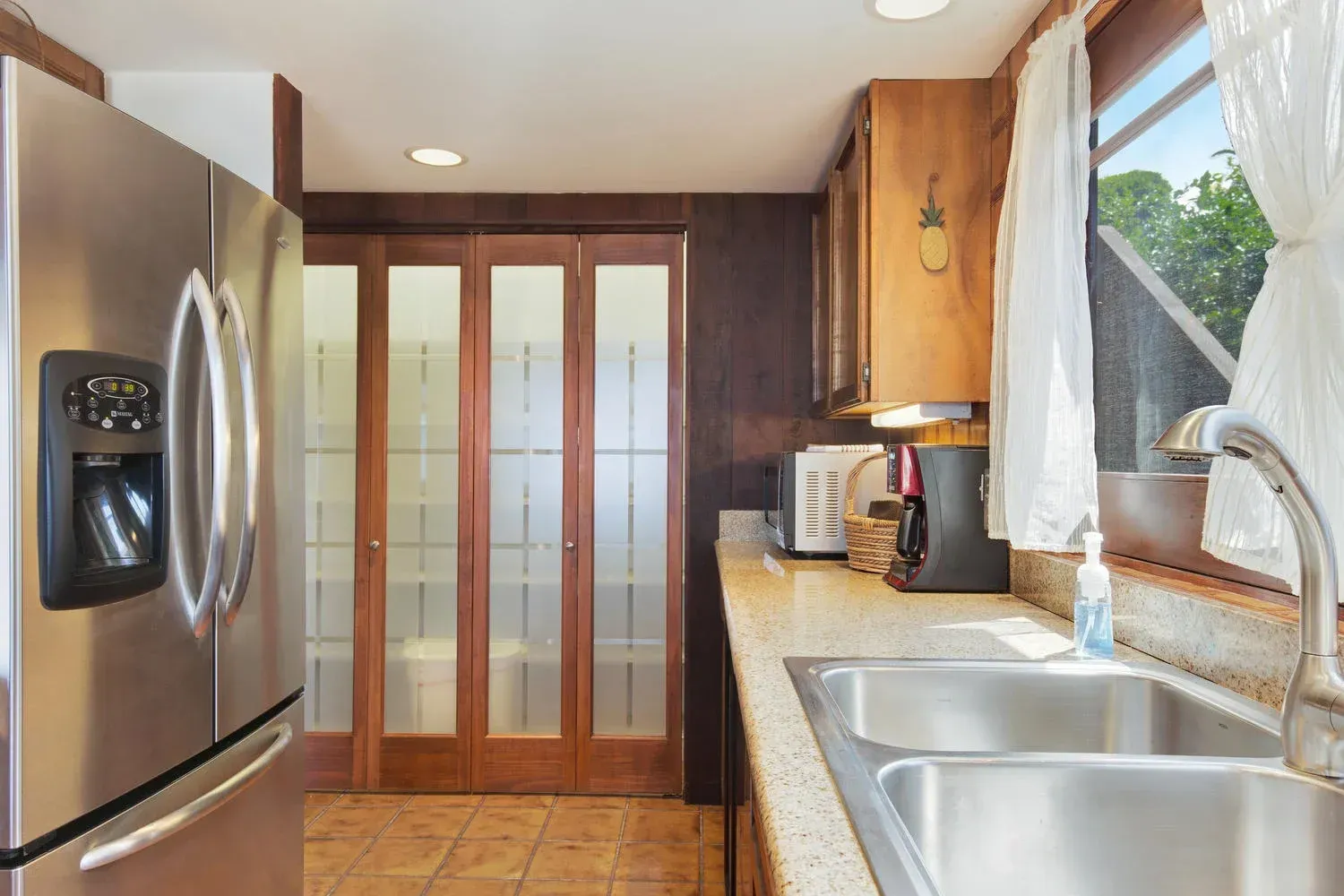 A kitchen with a stainless steel refrigerator , sink , and cabinets.
