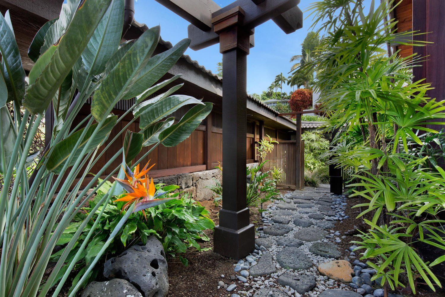 A lush green garden with a stone path leading to a house