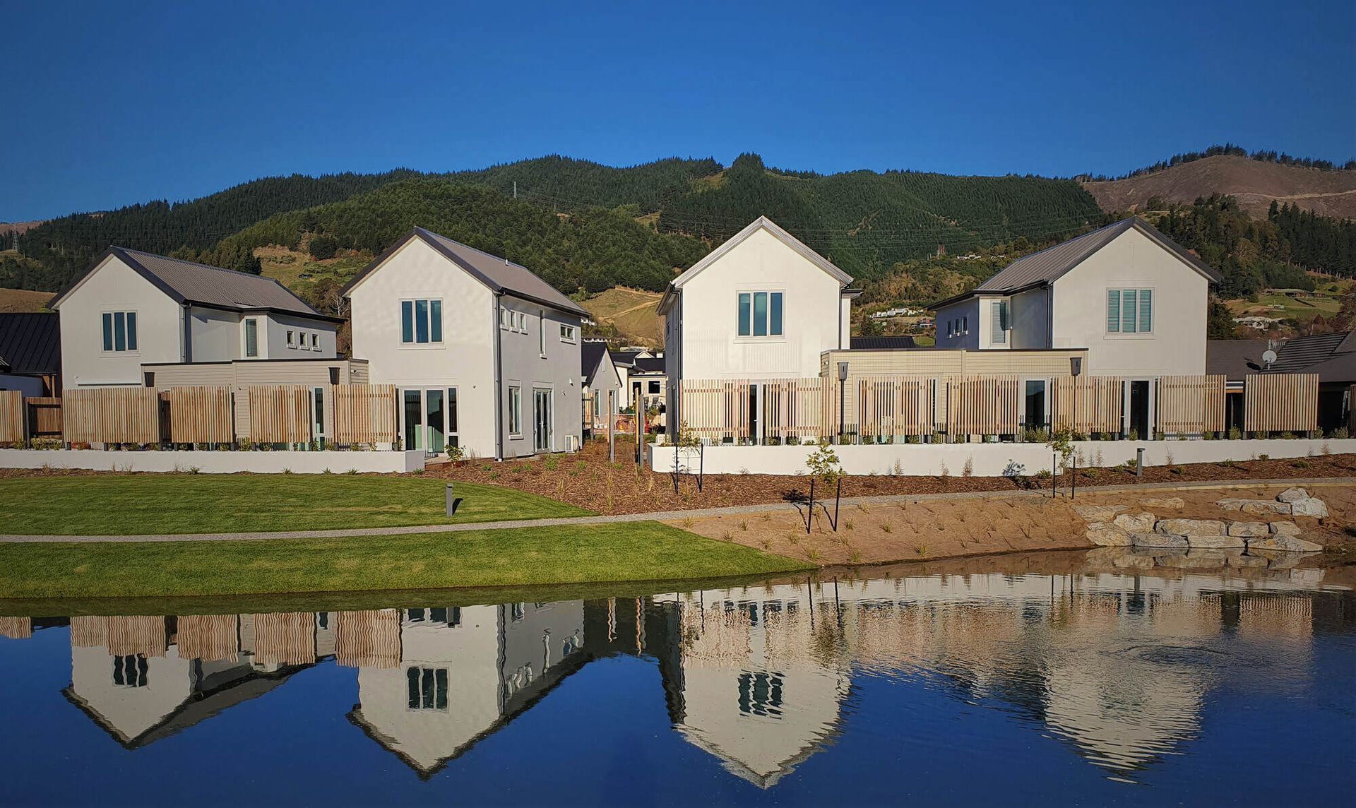 A row of houses are reflected in a body of water.