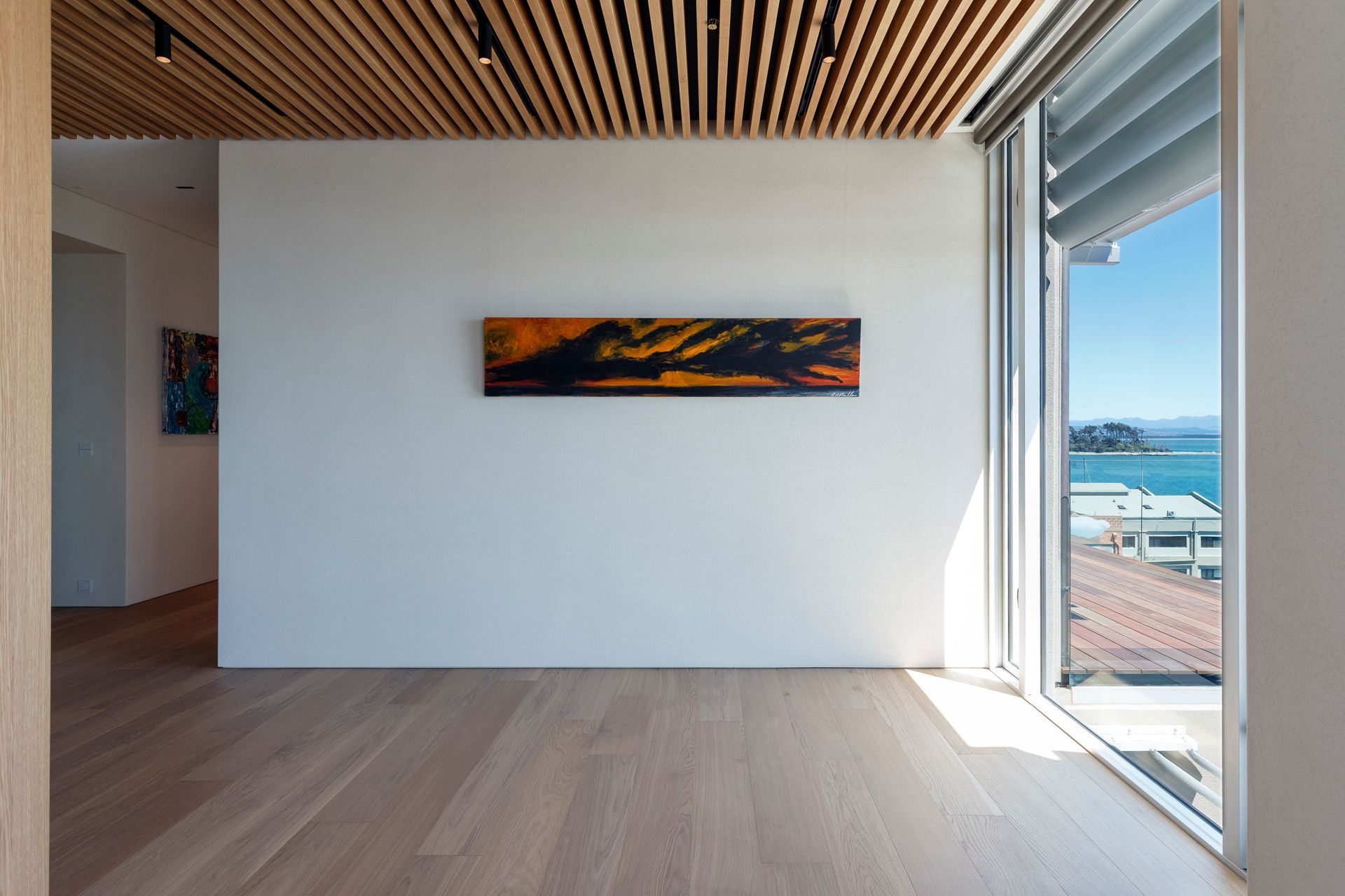 A room with a large window and a painting on the wall.