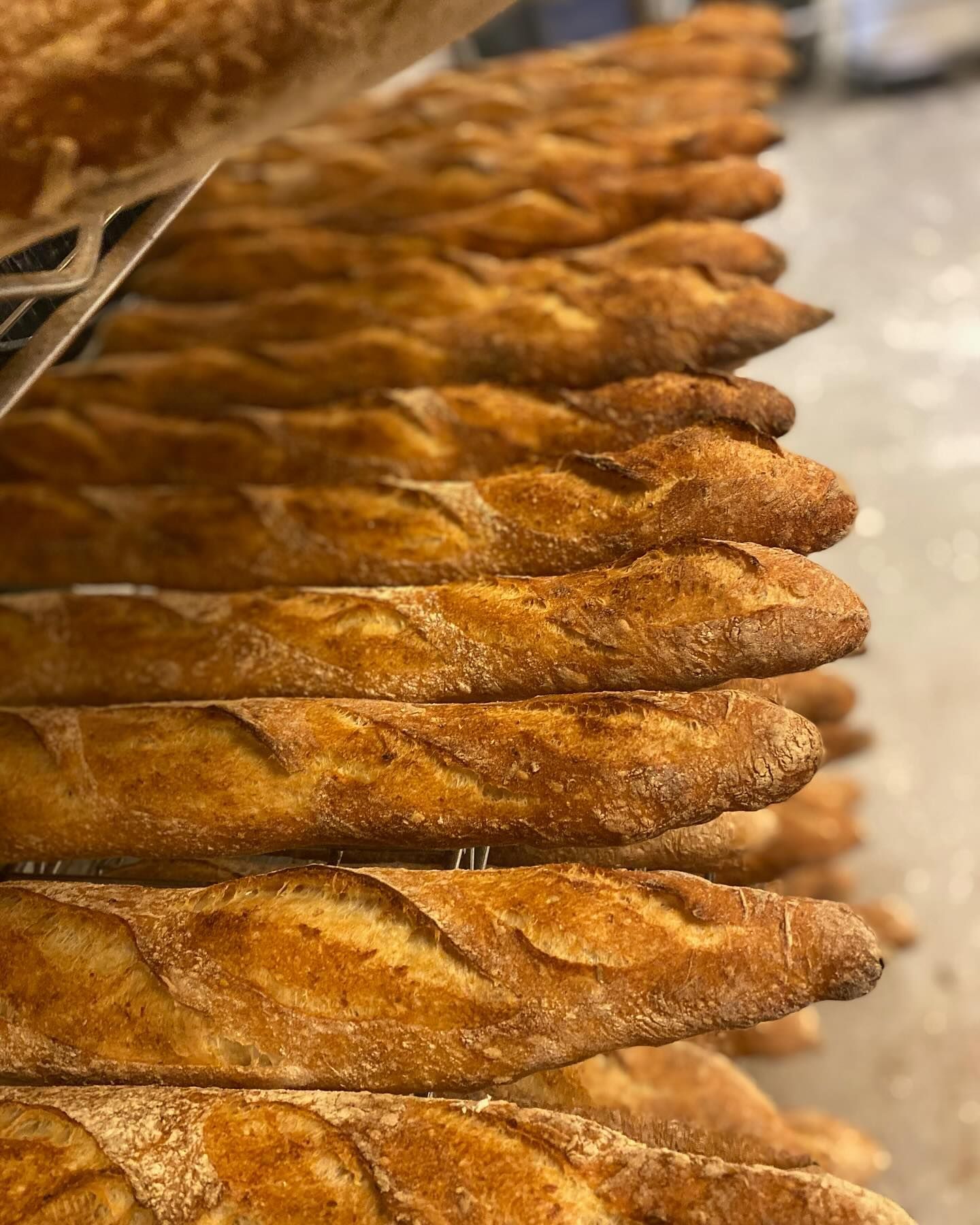 A bunch of baguettes are stacked on top of each other in a bakery.