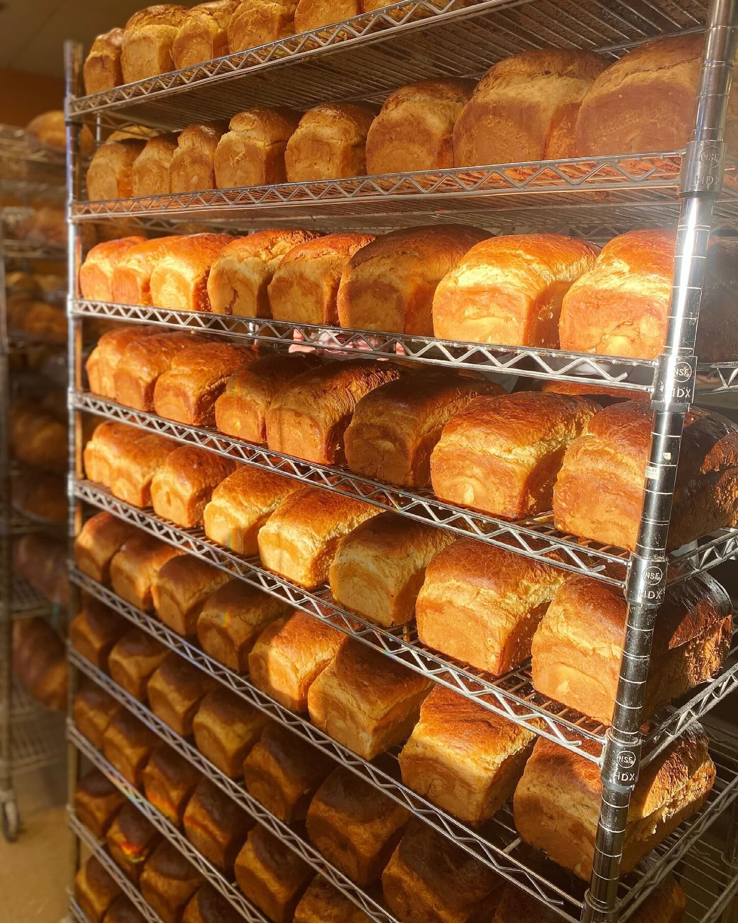 A bunch of bread sitting on a rack in a bakery