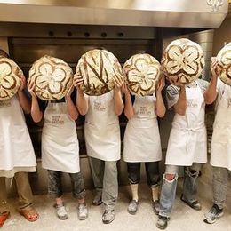 A group of people are holding bread in front of their faces